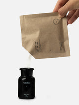 Terra Tonics Elemental Cleanser Refill – Natürlicher Reinigungspuder wird aus der Nachfüllpackung in die schwarze Glasflasche umgefüllt.